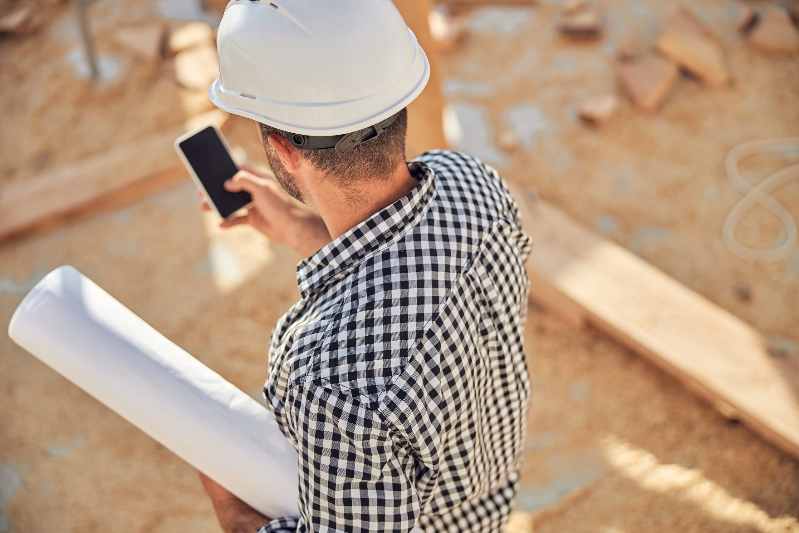 Busy architect with a roll of blueprints and a phone